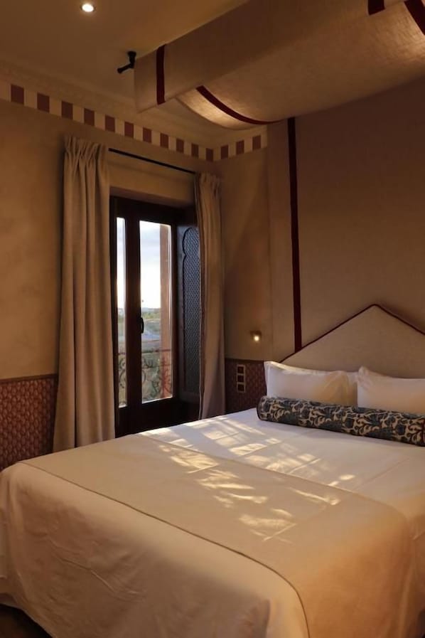 A hotel room with a large bed, a window with curtains, and a view of the outdoors.