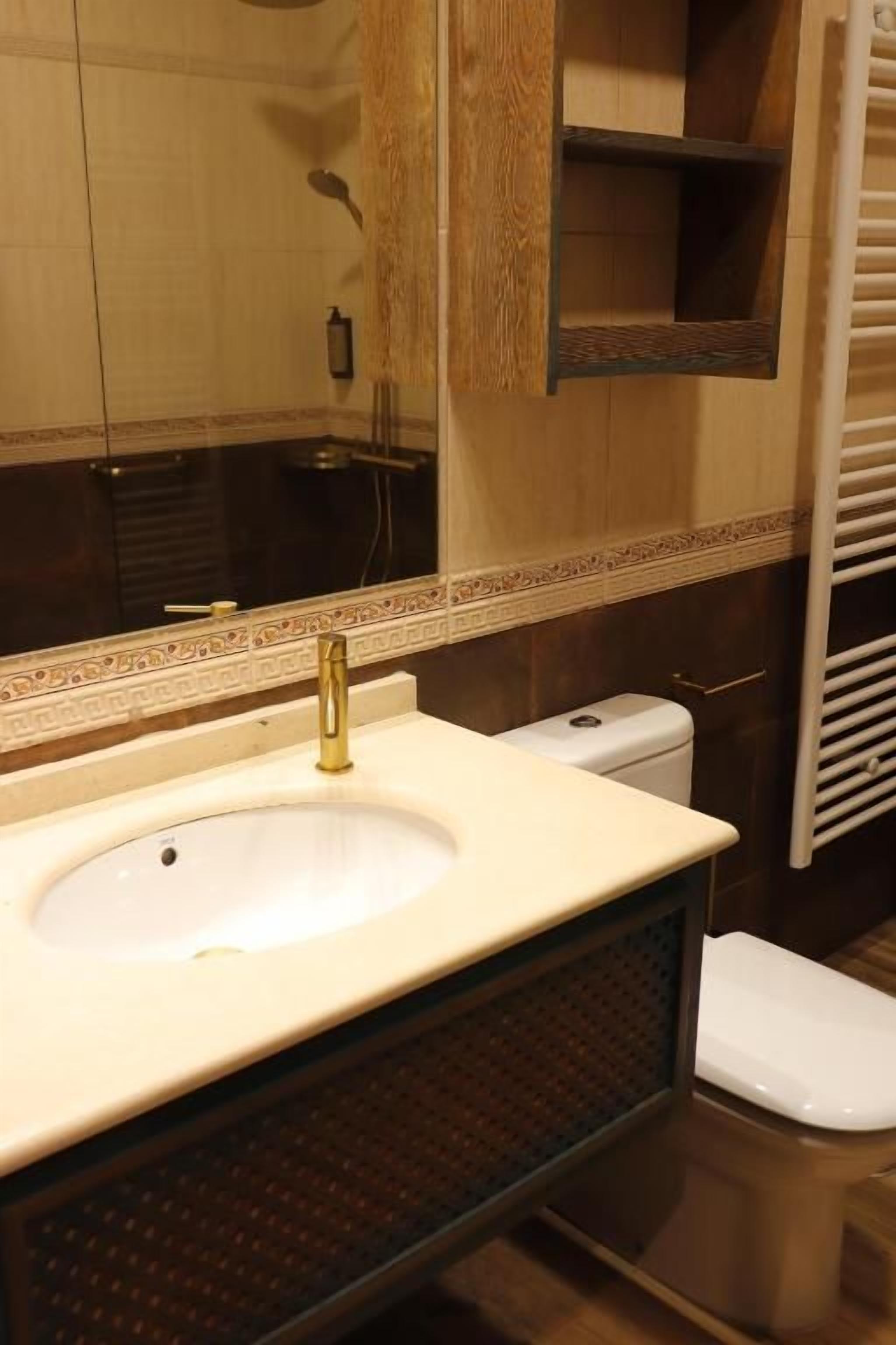Un baño con lavamanos, espejo e inodoro.