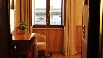 Una habitación de hotel con zona de comedor, ventana con cortinas y vistas al exterior.