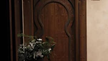 A wooden door with a number '203' above it, a potted plant to the left, and a wall-mounted air conditioning unit above.