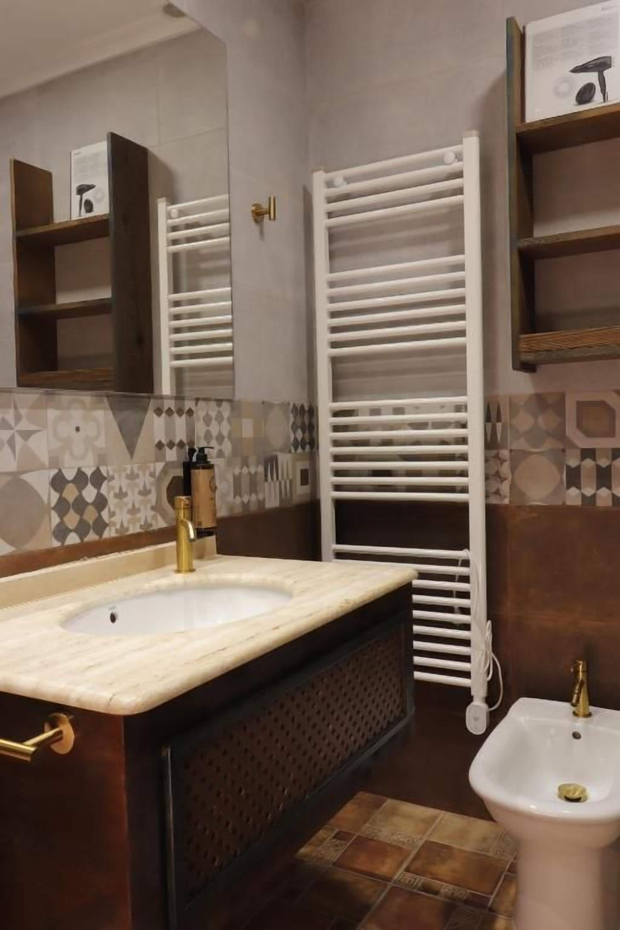 Un baño con lavamanos, espejo, toallero y bidé.
