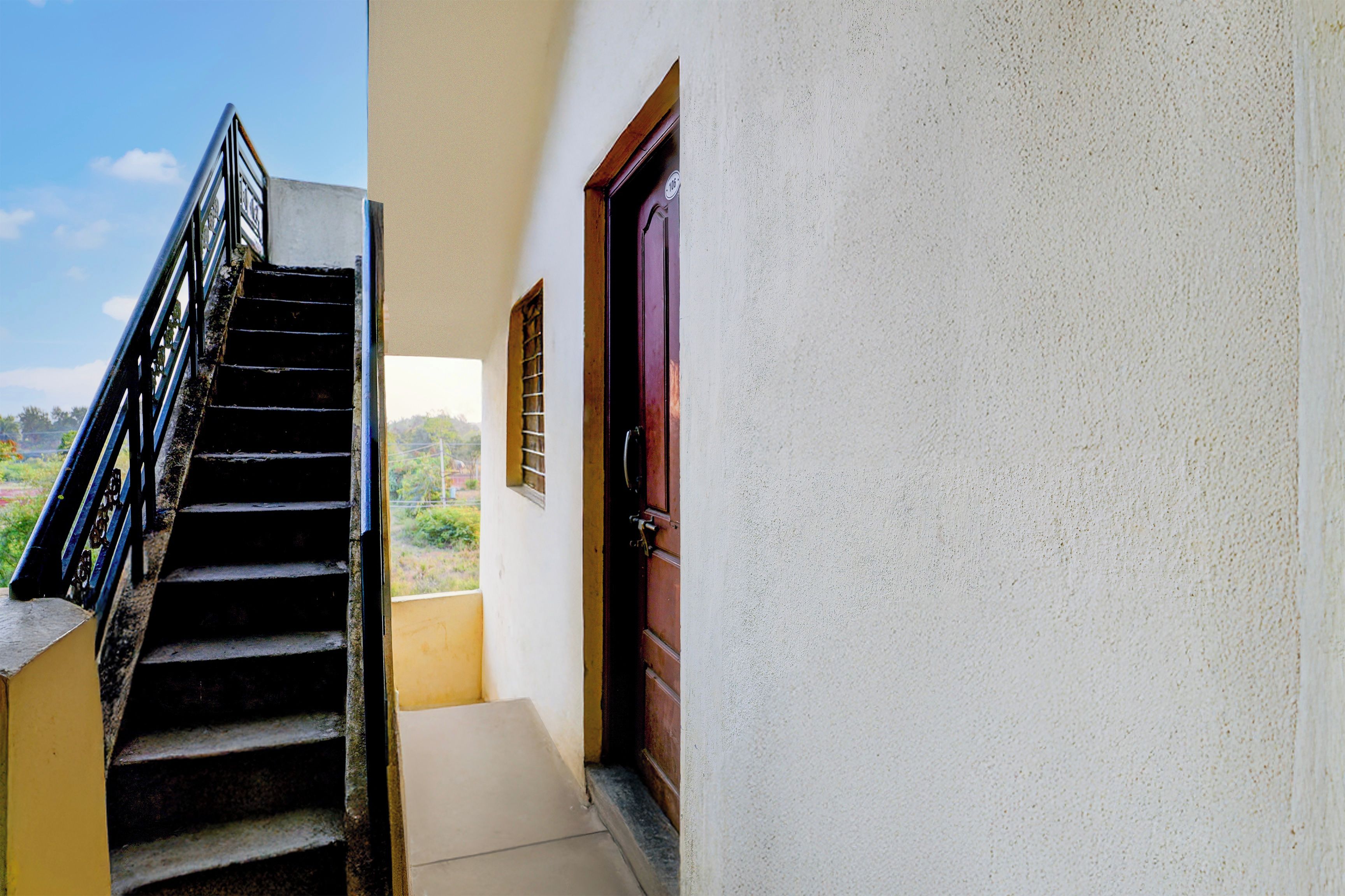 Una escalera conduce a un balcón con vistas a zonas verdes.