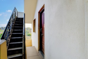 A staircase leading to a balcony with a view of greenery.
