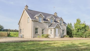A two-story house with a symmetrical facade, a central entrance, and a chimney.