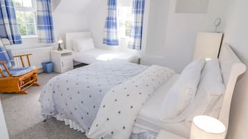 A bedroom with a bed, bedside table, lamp, and a chair.