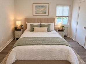 A neatly made bed with a headboard, two bedside tables with lamps, a framed picture on the wall, and a window with blinds. - Downtown &Stadiums 10 minute via T or rideshare 3 bedroom / 1 bath sleeps 6 (Pittsburgh)
