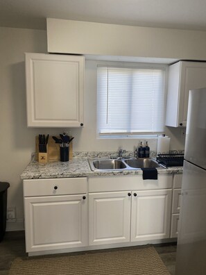 A kitchen with white cabinets, a granite countertop, a stainless steel sink, and a window with blinds. - Downtown &Stadiums 10 minute via T or rideshare 3 bedroom / 1 bath sleeps 6 (Pittsburgh)
