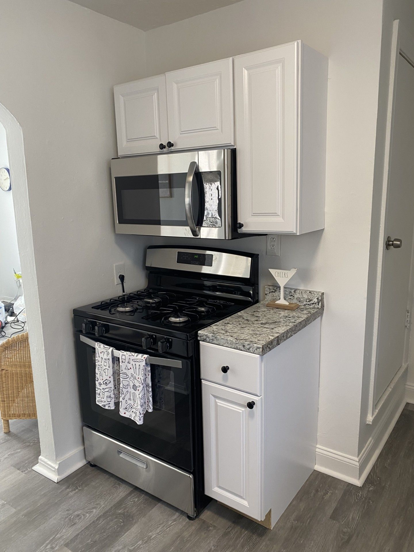 A kitchen with white cabinets, a stainless steel stove, a microwave, and a granite countertop.