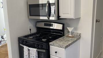 A kitchen with white cabinets, a stainless steel stove, a microwave, and a granite countertop.