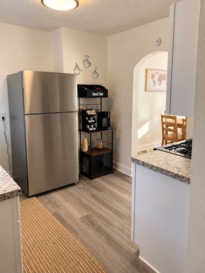 A kitchen with a stainless steel refrigerator, a snack bar shelf, and a dining area with chairs. - Downtown &Stadiums 10 minute via T or rideshare 3 bedroom / 1 bath sleeps 6 (Pittsburgh)