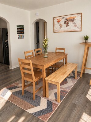 A dining area with a wooden table and chairs, a bench, a world map on the wall, and a small potted plant on a side table. - Downtown &Stadiums 10 minute via T or rideshare 3 bedroom / 1 bath sleeps 6 (Pittsburgh)