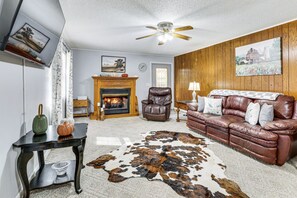 A living room with a fireplace, leather sofa, and a cowhide rug. - Cozy Soddy-Daisy Home w Fire Pit & Porch (Soddy-Daisy)