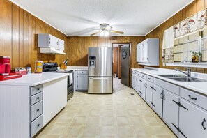 A kitchen with wooden paneling, stainless steel appliances, and white cabinetry. - Cozy Soddy-Daisy Home w Fire Pit & Porch (Soddy-Daisy)