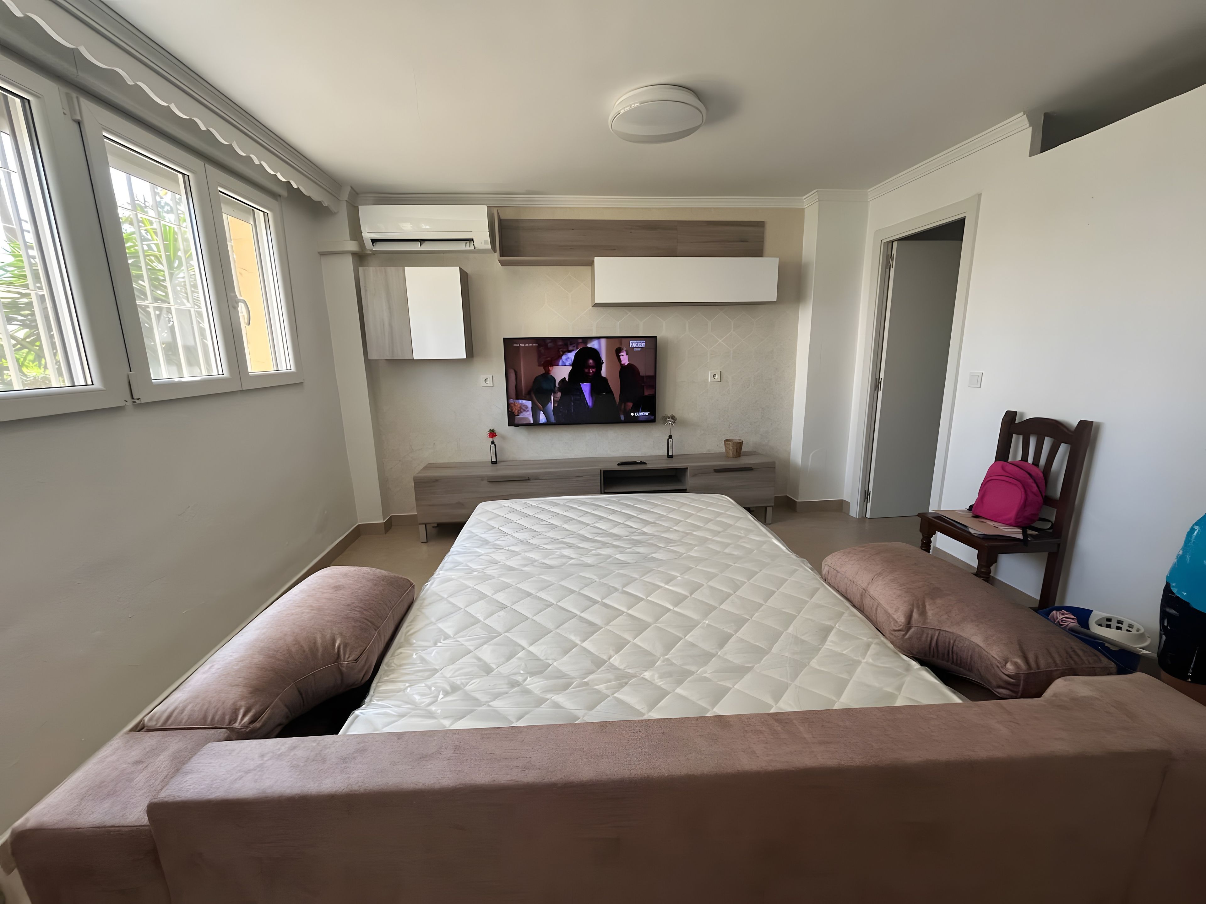 Un dormitorio con cama, televisor, cómoda y silla.
