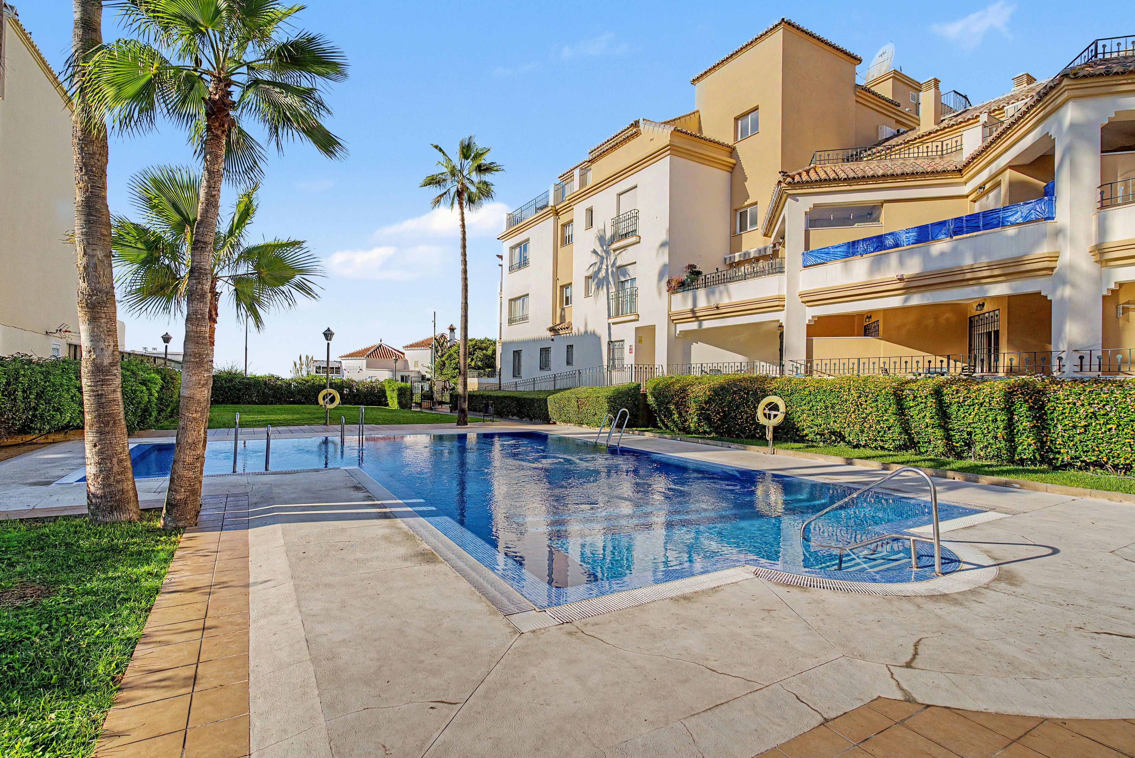Ein Swimmingpool mit Palmen und einem Gebäude mit Balkonen.