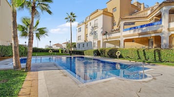 Ein Swimmingpool mit Palmen und einem Gebäude mit Balkonen.