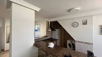 A kitchen with a granite countertop, a built-in oven, a microwave, and a washing machine.