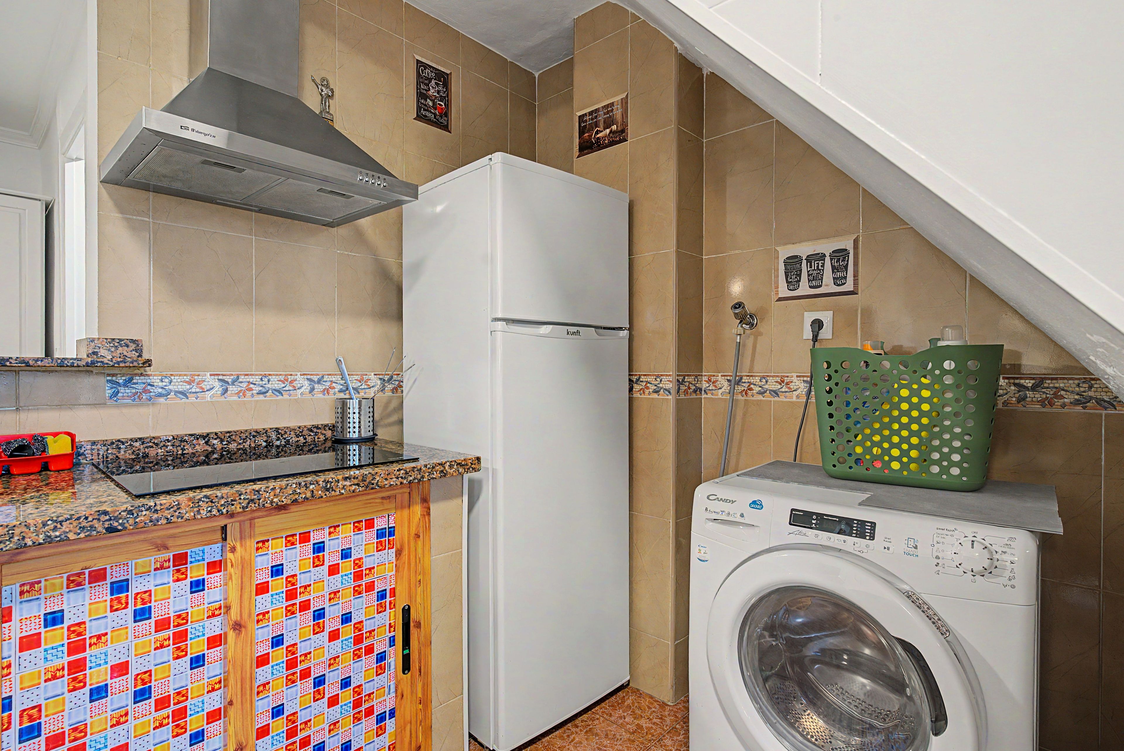 A kitchen with a refrigerator, washing machine, and a tiled backsplash.