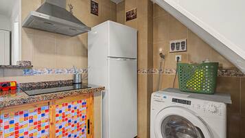 A kitchen with a refrigerator, washing machine, and a tiled backsplash.