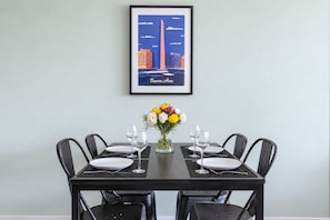 A dining table set for four with a framed cityscape poster above it. - New Apartments in Palermo by BueRentals (Buenos Aires)
