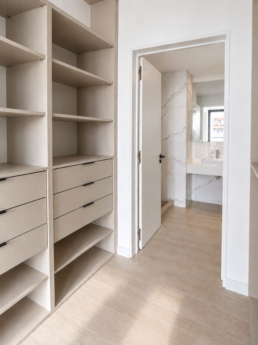 A hallway with a white wardrobe, a door leading to a bathroom with a marble wall, and a wooden floor.