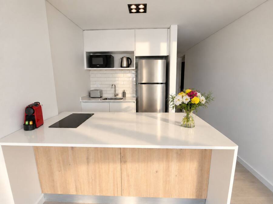 Una cocina moderna con una isla central, electrodomésticos de acero inoxidable y un diseño minimalista.
