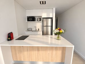 Une cuisine moderne dotée d’un îlot central, d’appareils électroménagers en acier inoxydable et d’un design minimaliste.