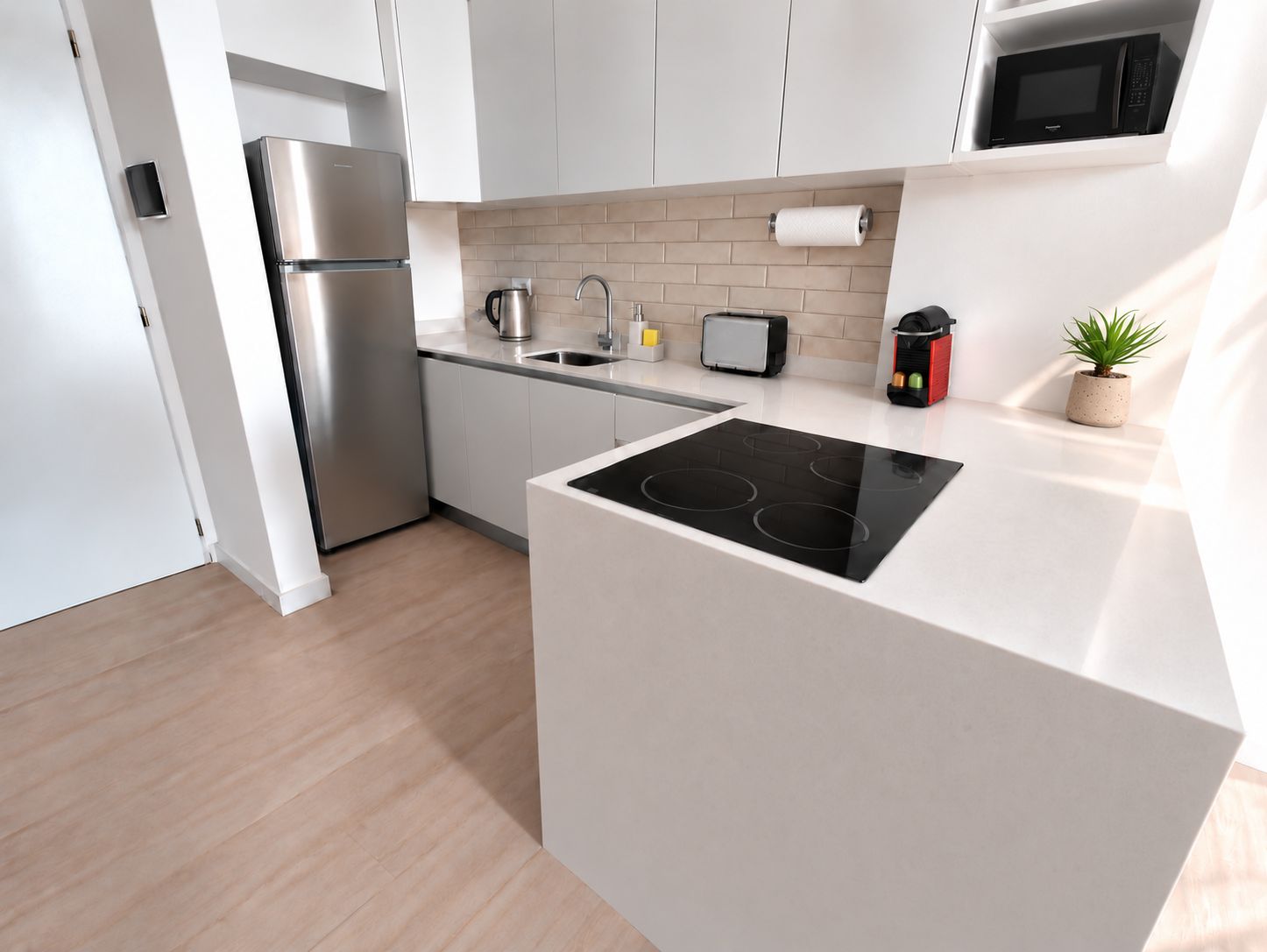 Una cocina moderna con estufa integrada, refrigerador de acero inoxidable y microondas.