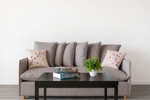 A grey sofa with floral cushions, a black coffee table, and a potted plant. - New Apartments in Palermo by BueRentals (Buenos Aires)