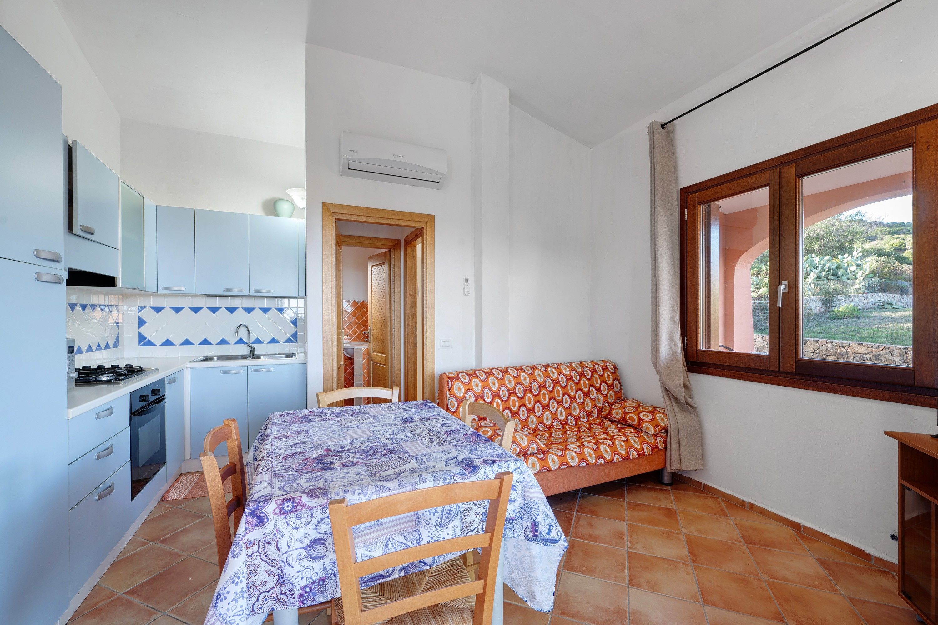 Una cocina compacta con una mesa de comedor y sillas, un sofá y un ventanal con vistas al verdor.