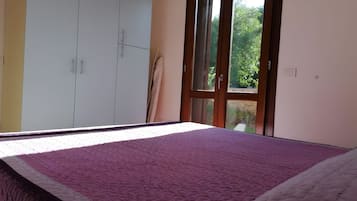 Un dormitorio con cama, armario y ventana con vistas a zonas verdes.