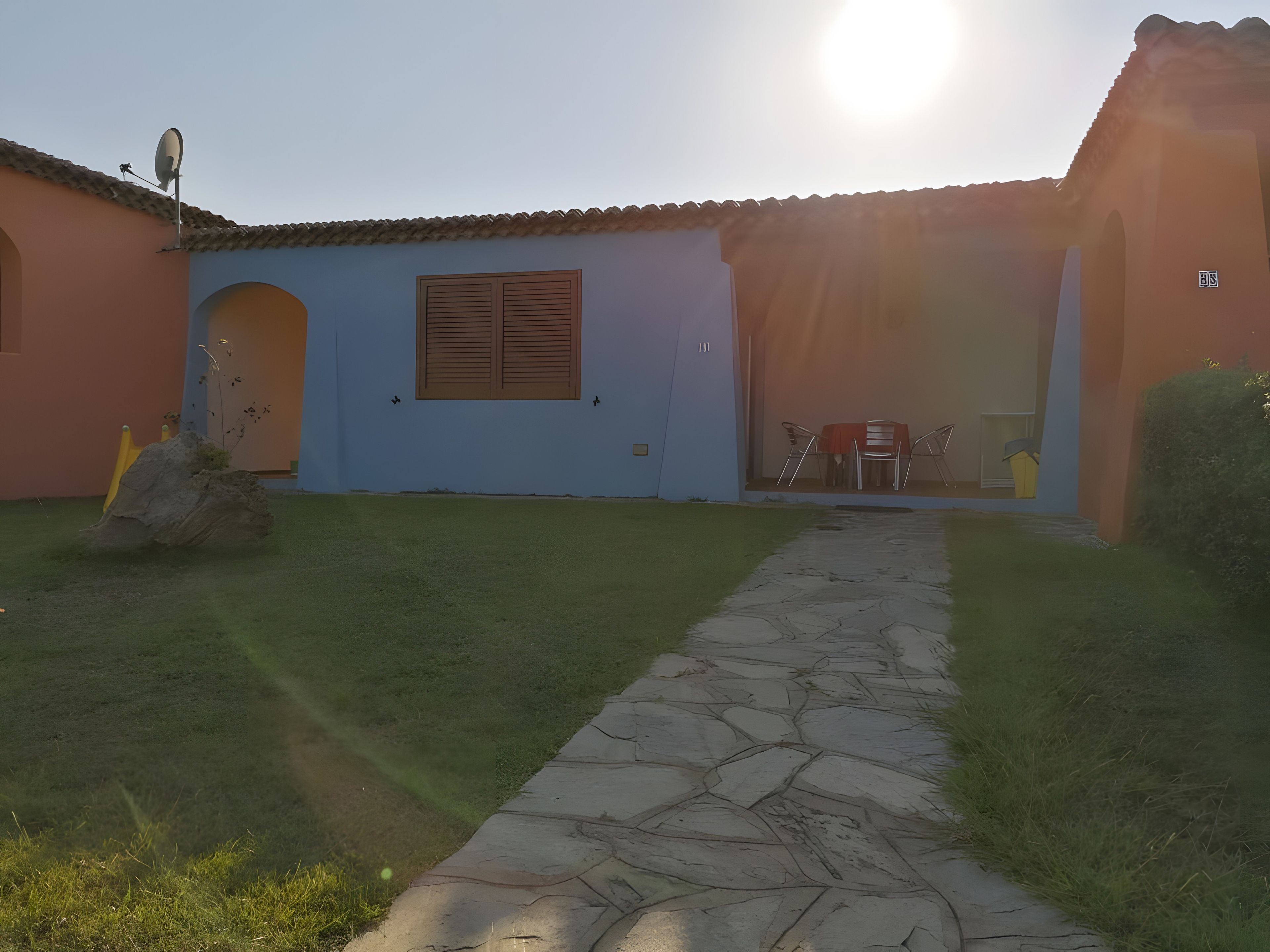 Un chemin menant à un bâtiment doté d’un toit en tuiles et d’une porte.