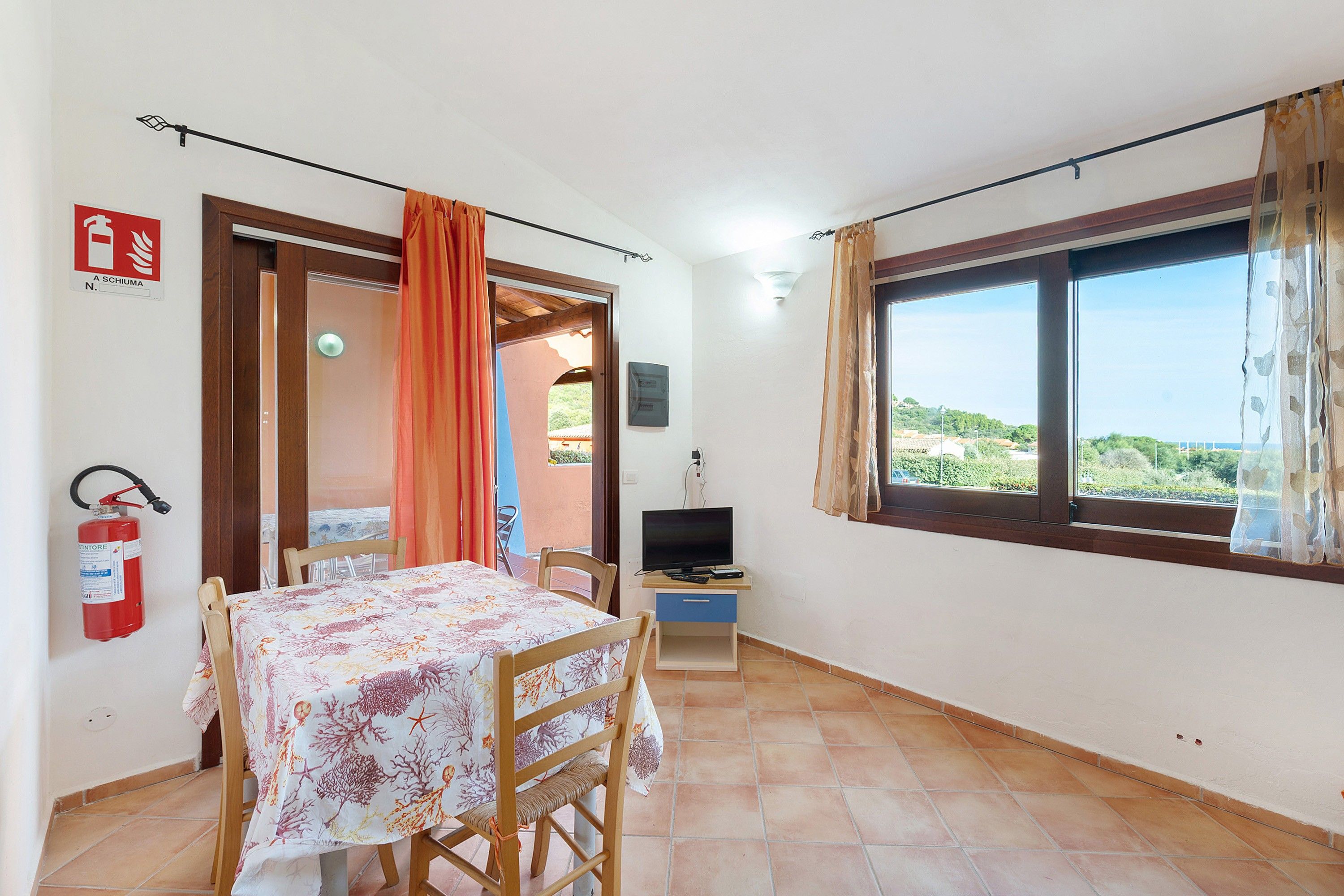 Una habitación con una mesa de comedor, sillas, un televisor y un ventanal con vistas.