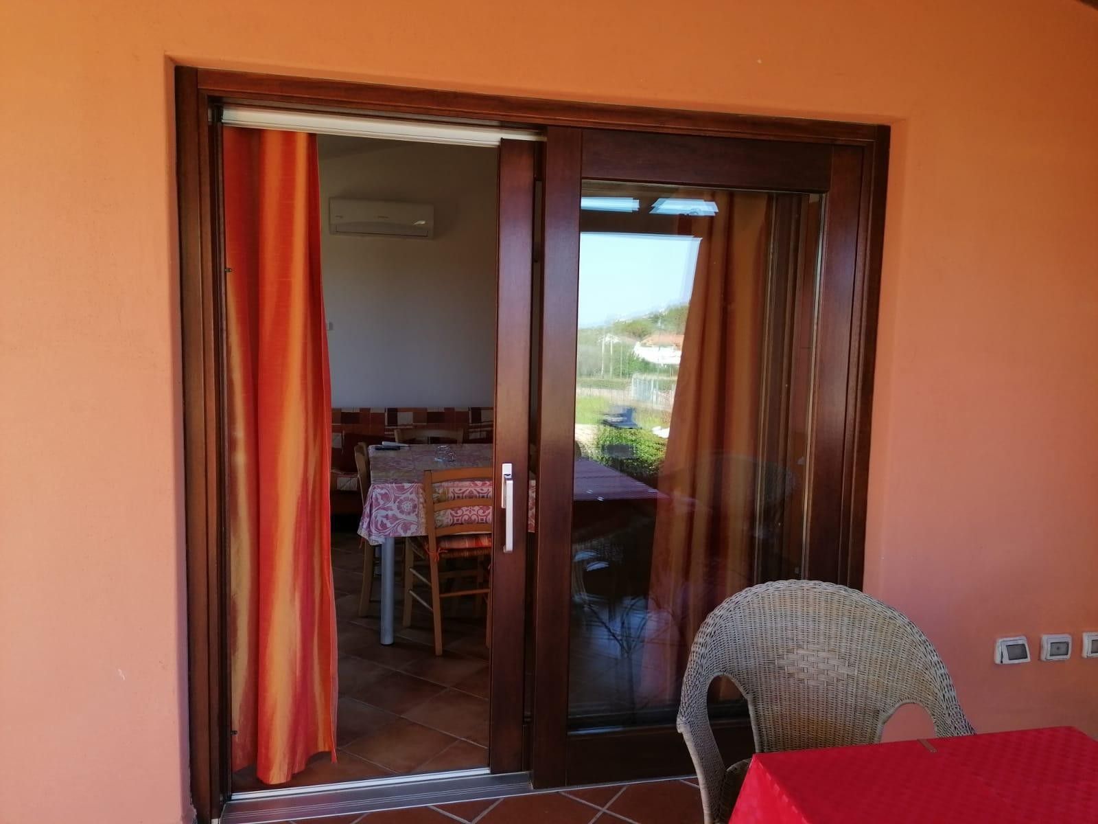Una habitación con puerta de vidrio corredera que da a un espacio exterior con una mesa y sillas.