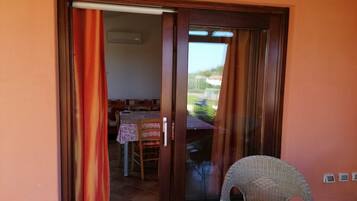 Una habitación con puerta de vidrio corredera que da a un espacio exterior con una mesa y sillas.