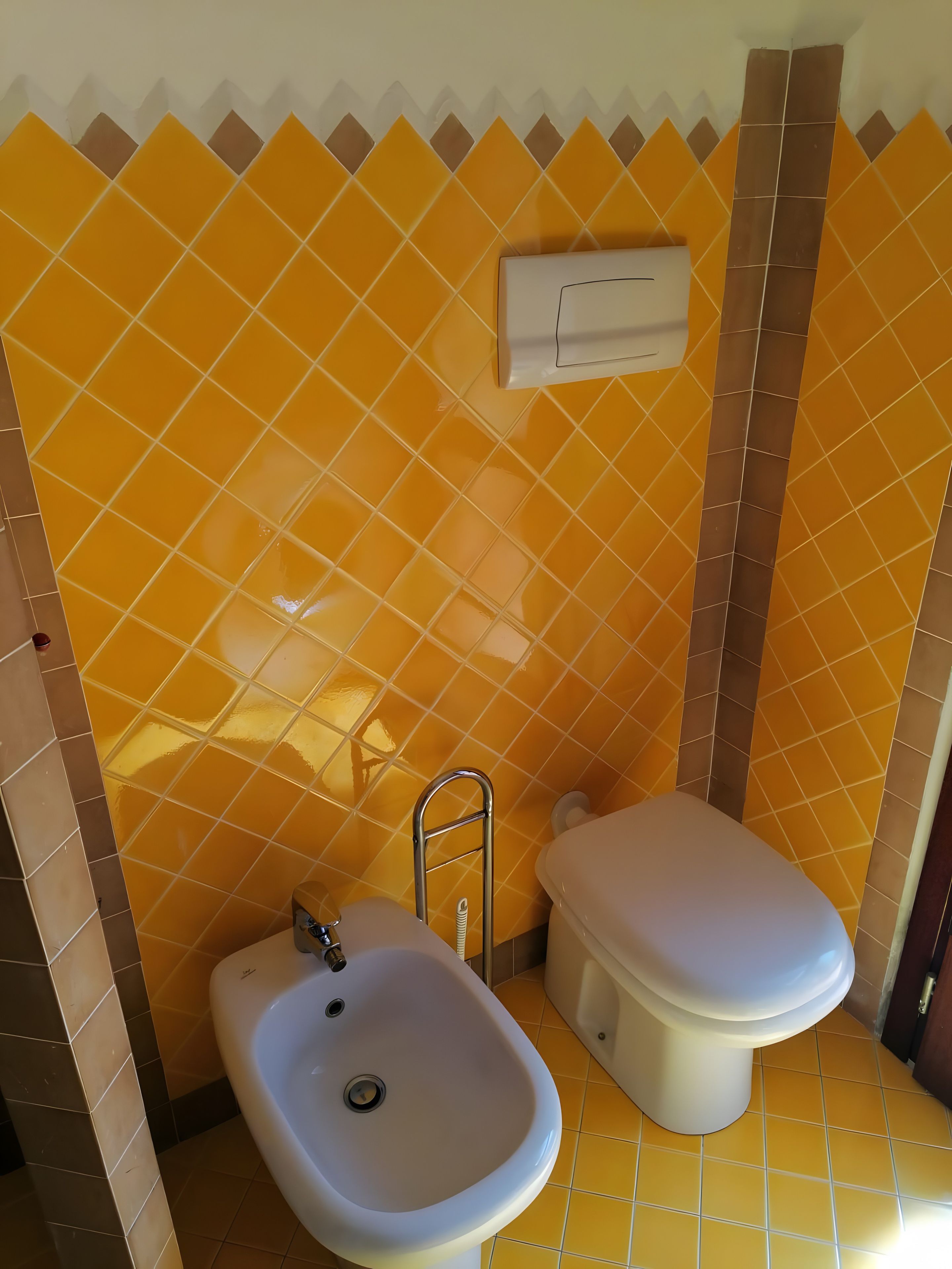 Un bagno con lavandino bianco, water e asciugamani a muro.