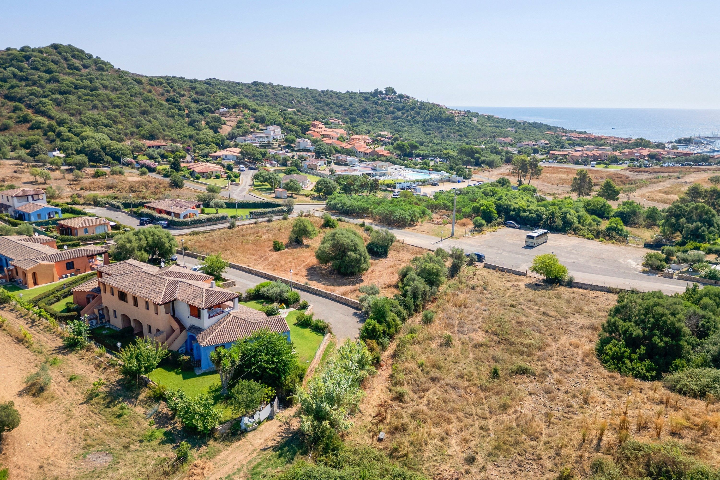 Un quartier résidentiel avec des maisons, une piscine et une vue sur la mer.