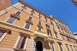 A multi-story building with a classic architectural style, featuring a central entrance with an archway, multiple windows with shutters, and a flat roof. - Maison Florienne: Charm and Relaxation in the Heart of Rome (Roma)
