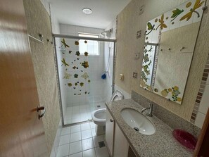 Ein Badezimmer mit Dusche, Toilette, Waschbecken und einem spiegel mit floralen Verzierungen.
