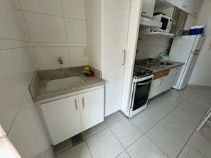Una cocina con armarios blancos, encimera de granito, estufa y refrigerador.