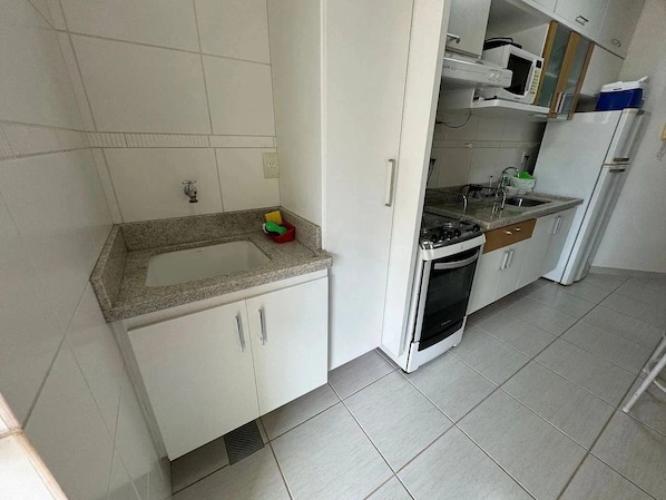 Una cocina con armarios blancos, encimera de granito, estufa y refrigerador.
