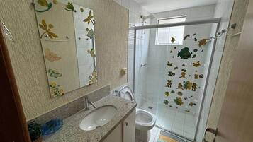 Casa de banho com lavatório, espelho e chuveiro.