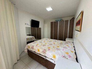 Ein Schlafzimmer mit einem Bett, einem Fernseher, einem Kleiderschrank und einem Bild an der Wand.
