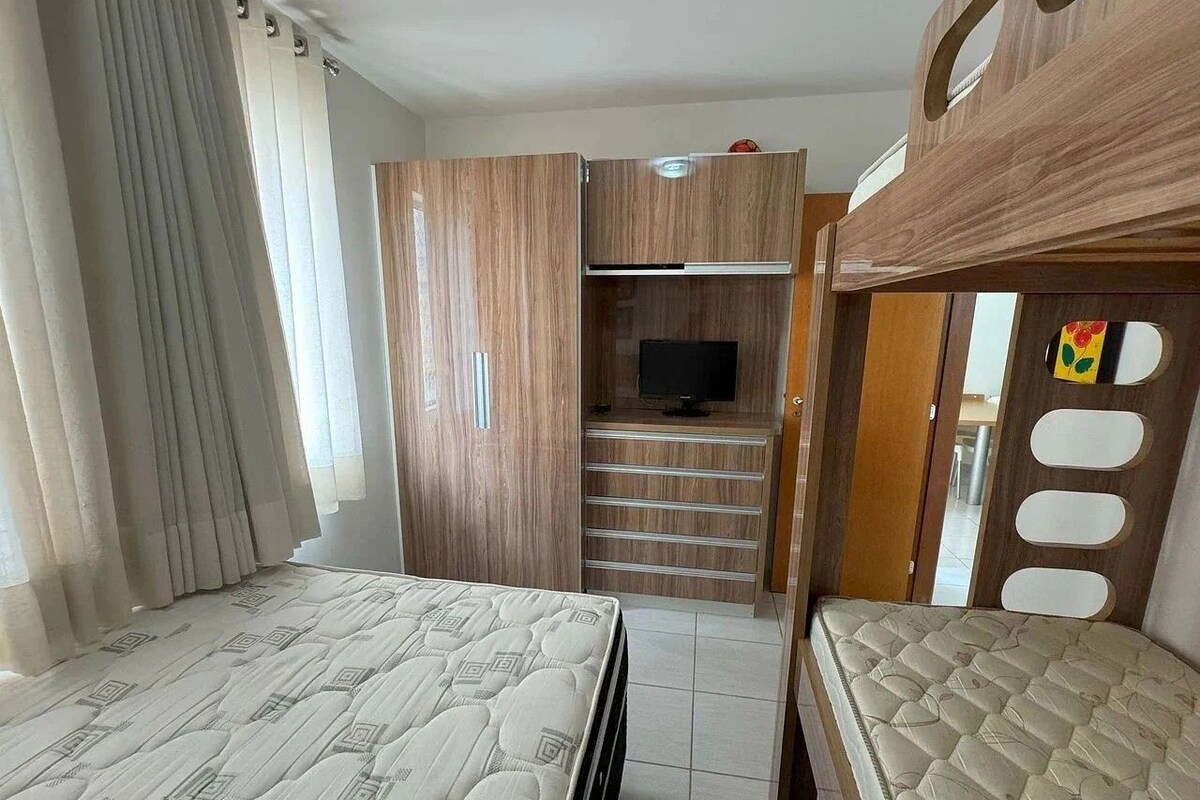 Ein Schlafzimmer mit Etagenbett, Kleiderschrank, Fernseher und Schreibtisch.