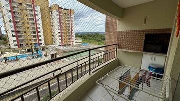 Varanda com vista para edifícios altos, piso ladrilhado e corrimão de metal.