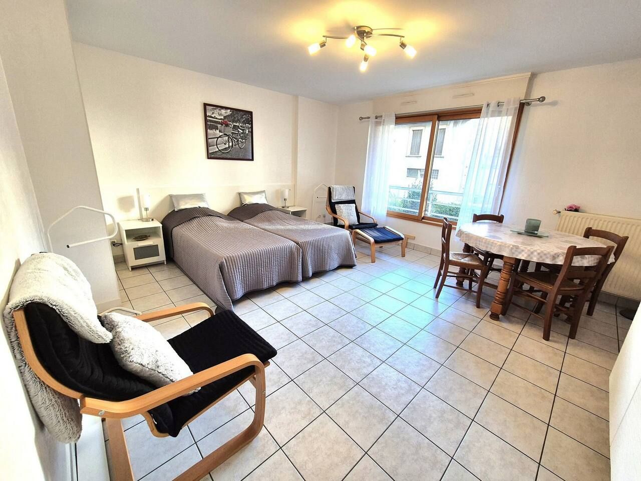 Une chambre d’hôtel avec un lit, une chaise, une table et une fenêtre avec des rideaux.