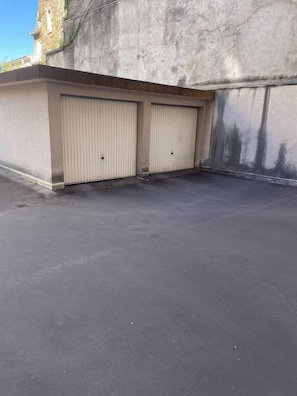 A flat rooftop with two closed garage doors and a concrete wall. - 33-square-meter studio, Wi-Fi, downtown location, and garage (Aix-les-Bains)