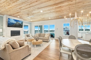A spacious living area with a fireplace, a large TV, and a dining table with chairs. - Amberjack | 7BR | Heated Pool & Spa | Sleeps 16 (Inlet Beach)