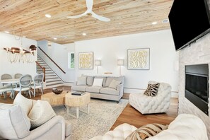 Una sala de estar moderna con techo de madera, chimenea y escalera.