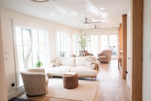 A spacious living room with a large sofa, a patterned armchair, and a wooden coffee table. - Bella Vista | Lakefront 30A | Dock & Kayaks (Seacrest)